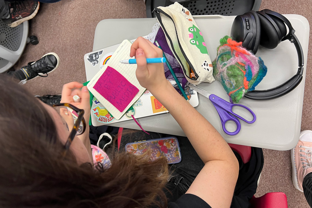 a top down view of a student making patches and buttons