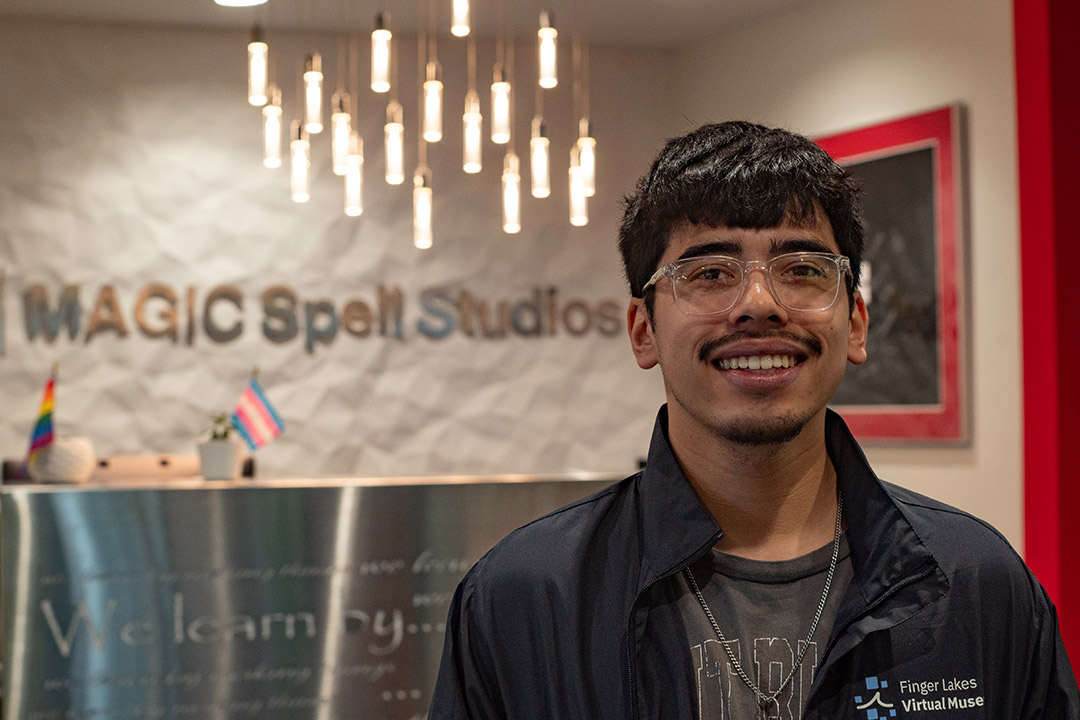 a college age male stands smiling in the lobby of magic spell studios