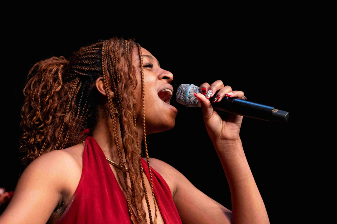 a young woman sings in to a microphone on stage