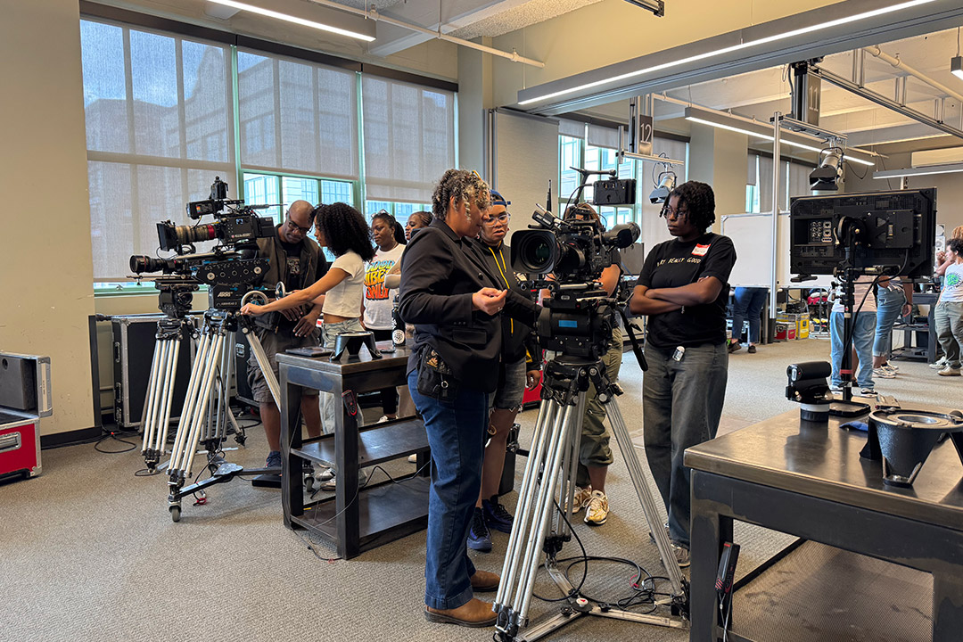 a young person learns to work a film camera.