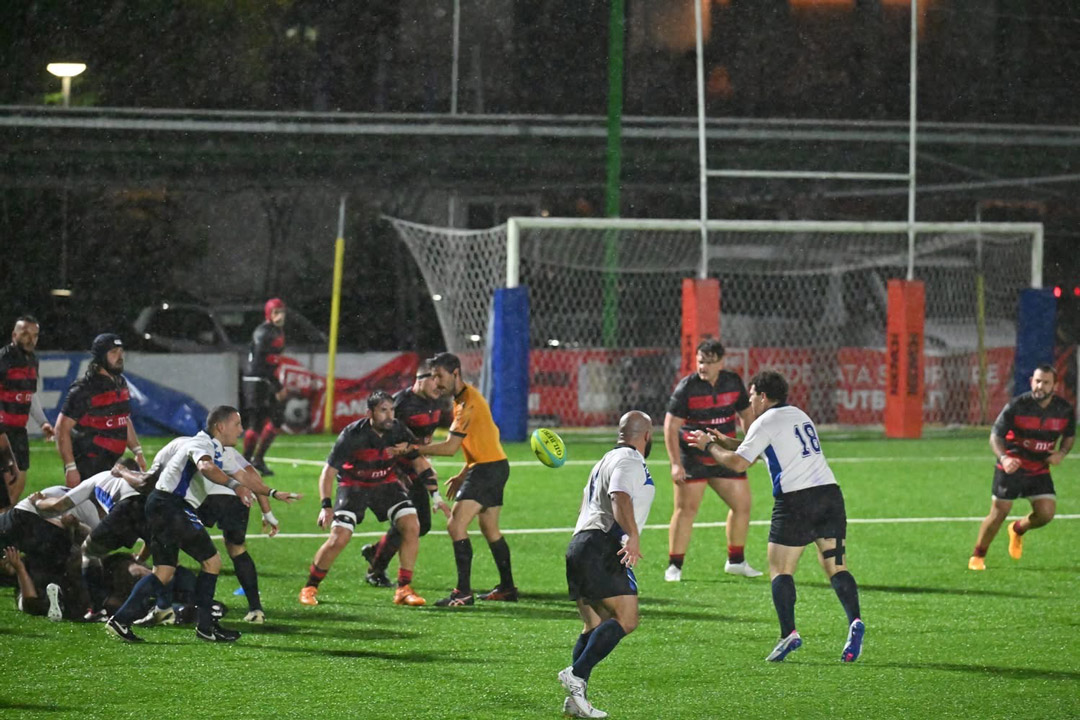 men play soccer on a pitch in the evening.