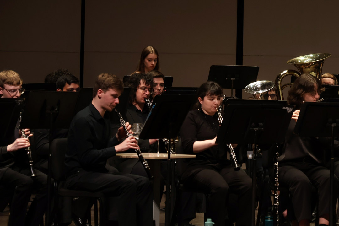 students dressed in black play in an orchestra on stage