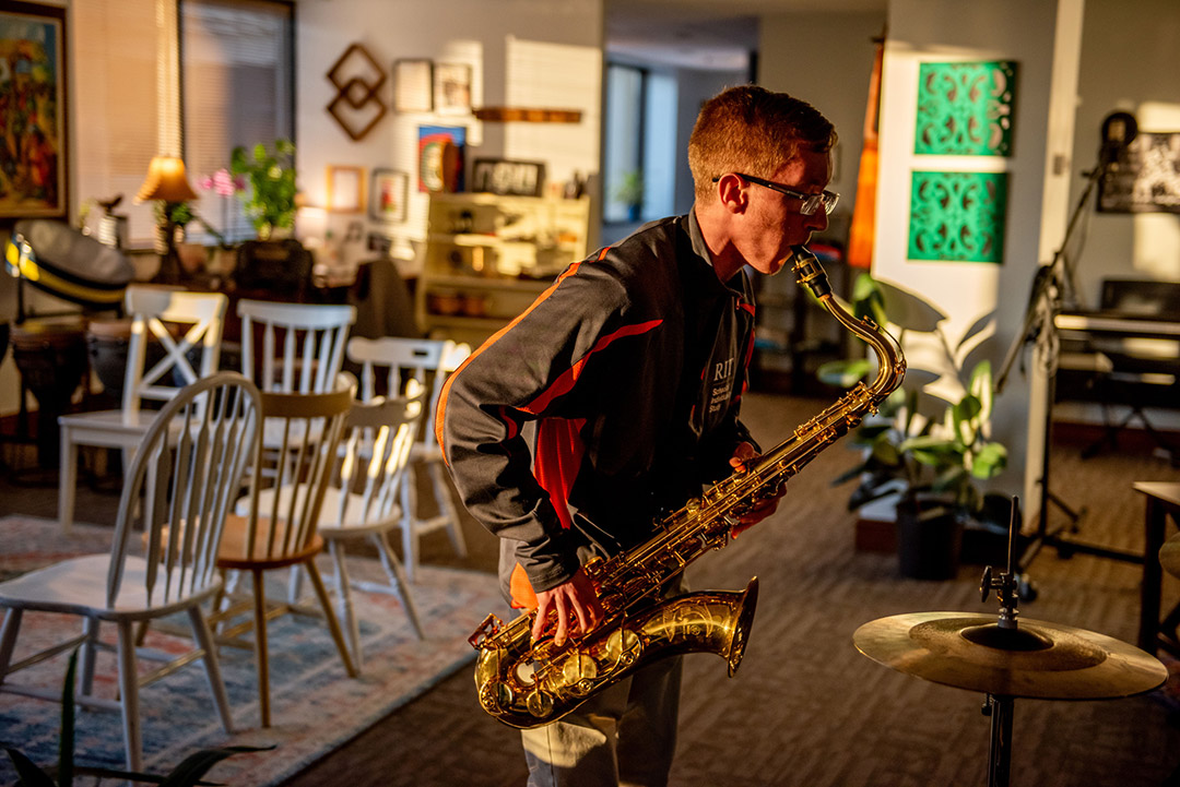 a man plays a saxaphone in a room filled with musical equipment.