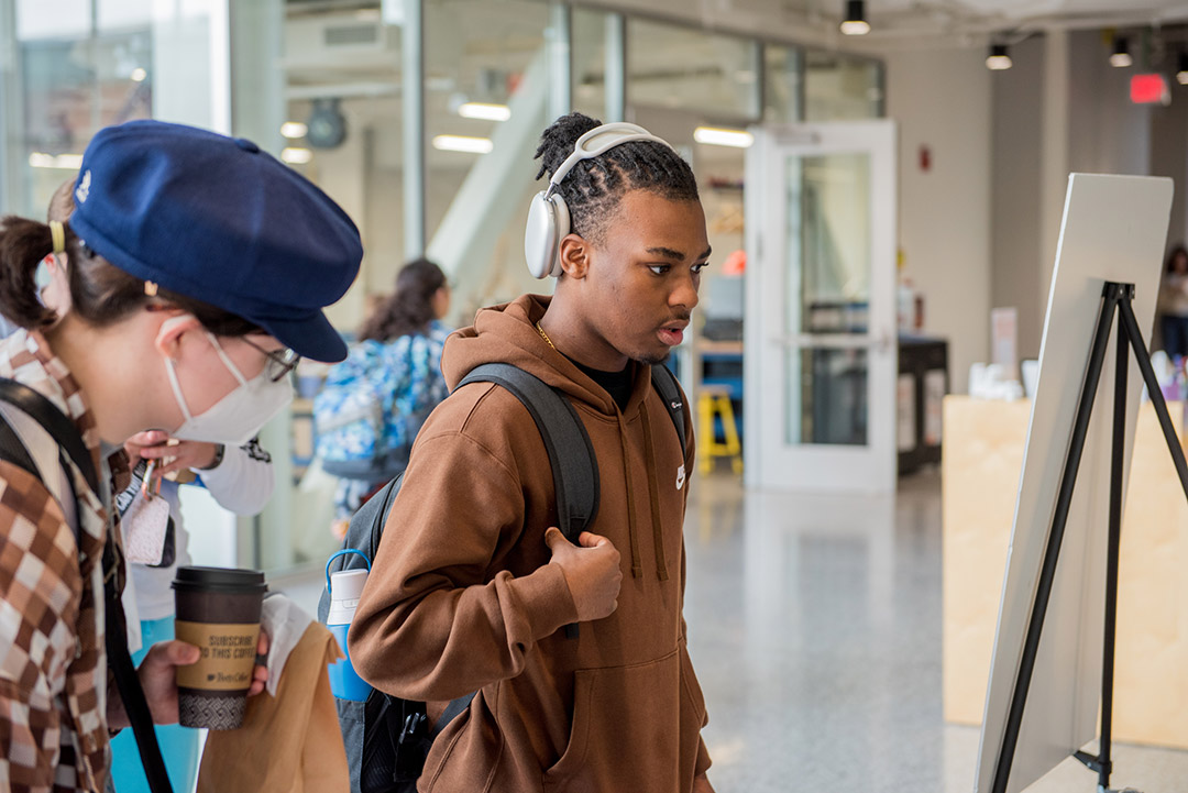 a young black male stands at a table advertising information on how to vote.