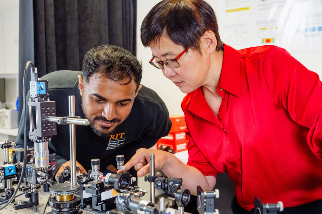 Researchers examine a photonics experiment together in an RIT laboratory.