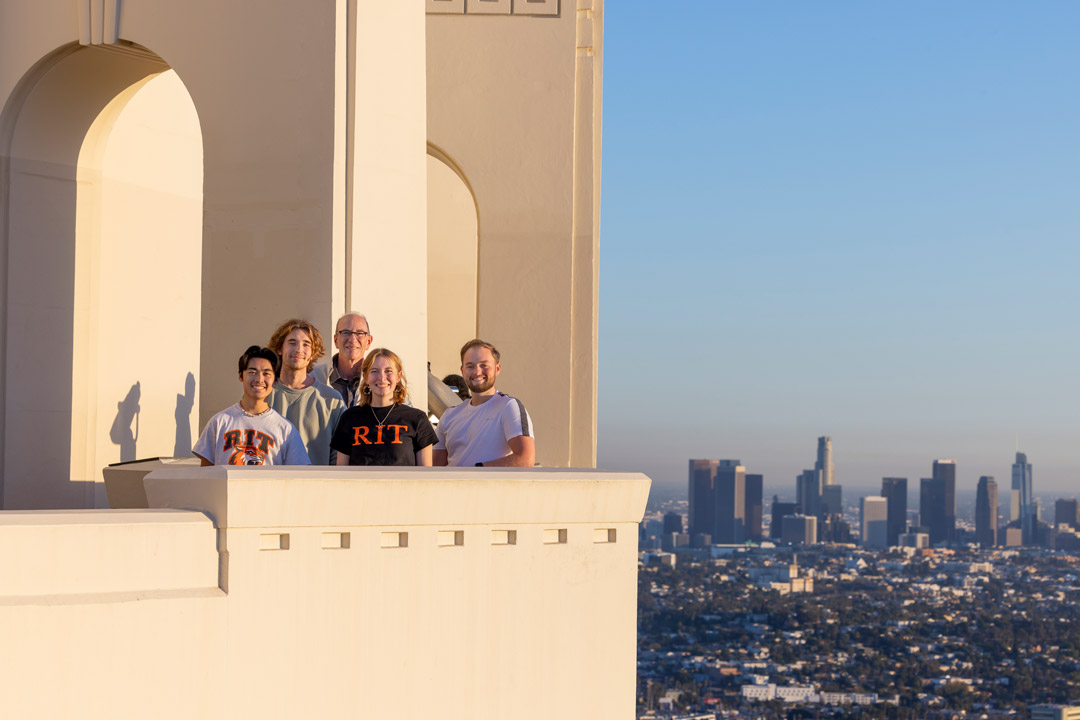 students stand on a balcony with hollywood in the background