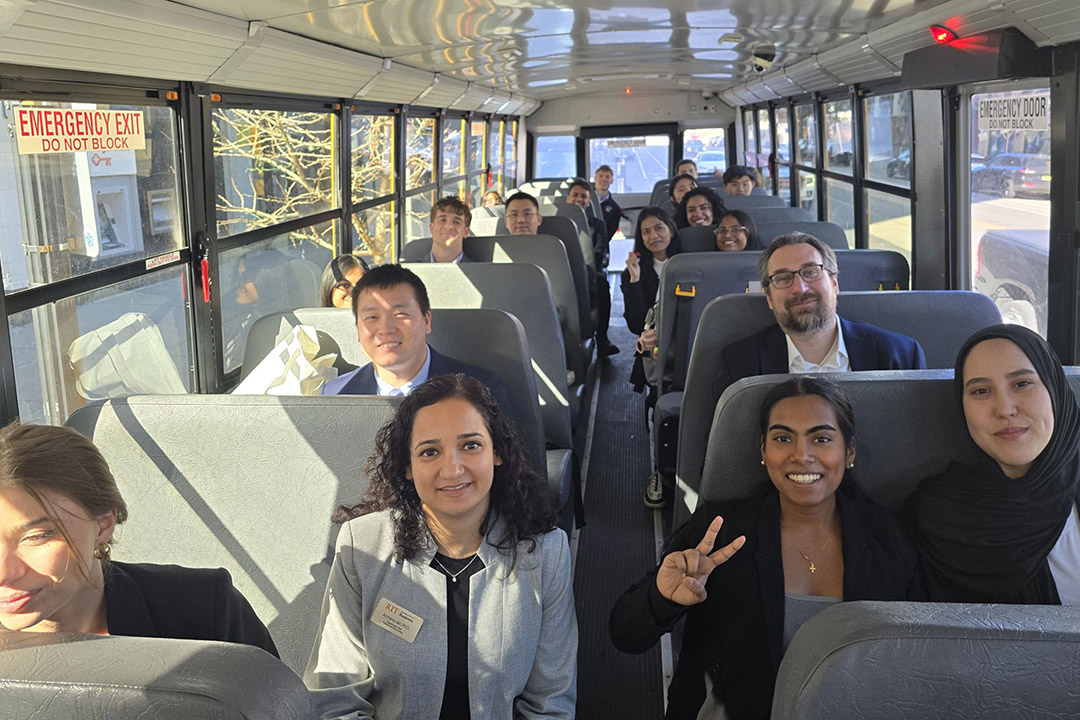 students sit on a bus and smile for the camera