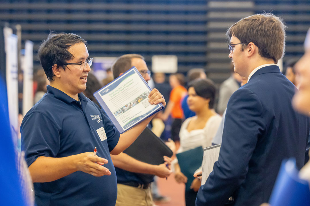 RIT alumnus Andrew Myers, left, explains opportunities available at Naval Nuclear Laboratory with Samuel Keniston, a second-year electrical engineering major 