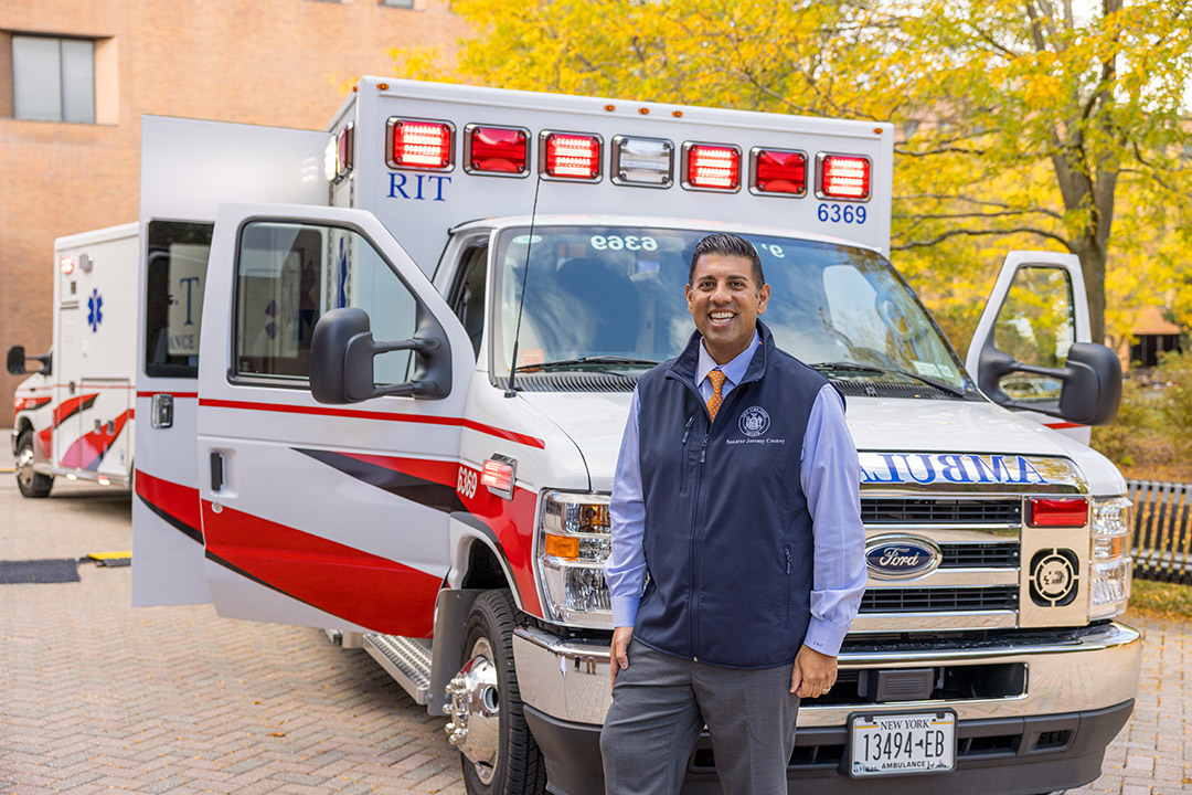 New York Senator Jeremy Cooney stands in front of an ambulance