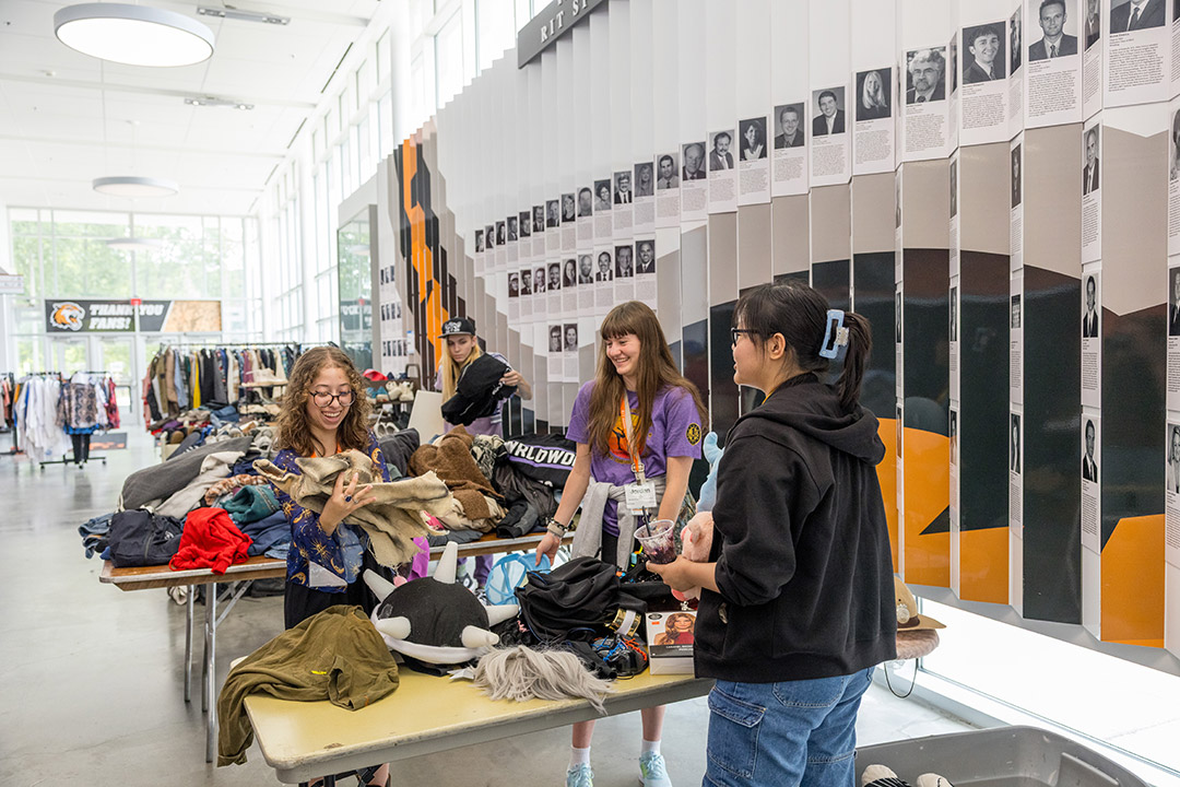three college age woman sift through donated clothing in a light filled hallway.