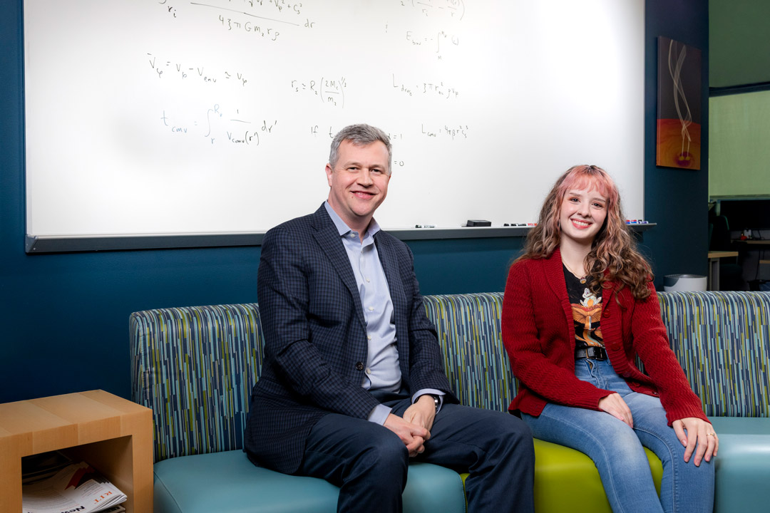 two people sit on a couch in a classroom environment
