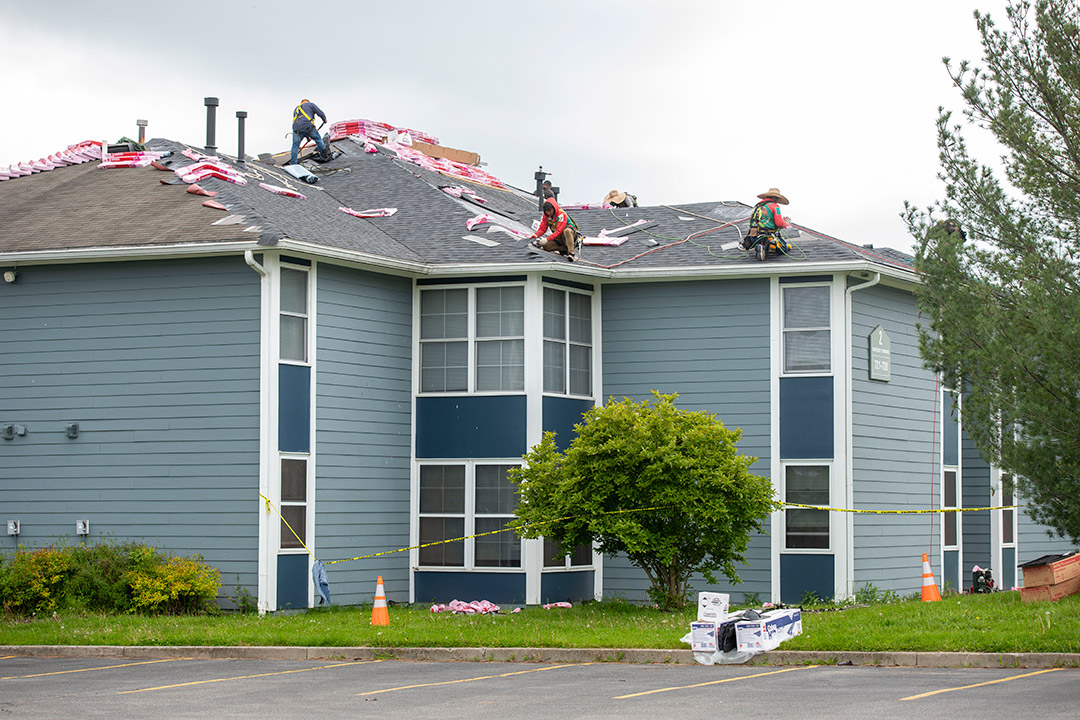 Roofers are seen making improvements on campus apartment housing.