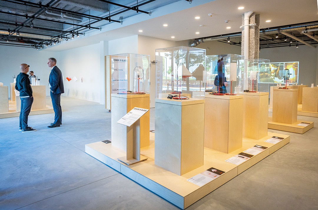 two men stand off to the side talking together in an art gallery setting.