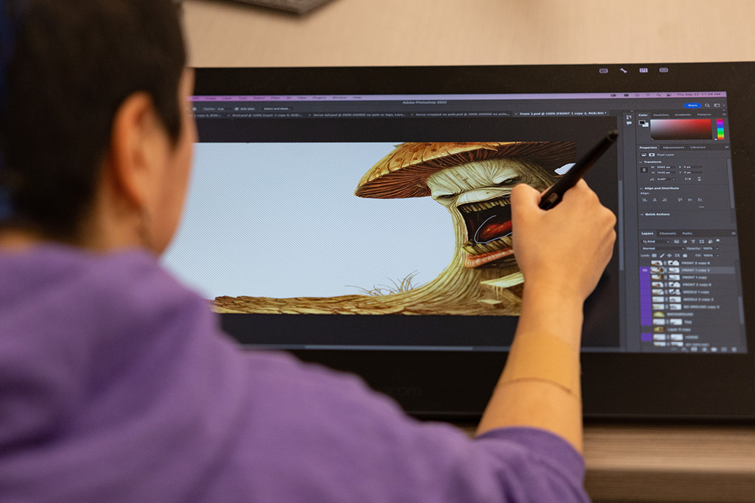 Artist uses a stylus to draw a roaring mushroom character in Photoshop on a pen display
