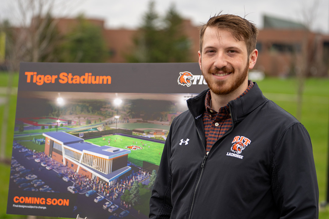 Connor Flanegan is pictured standing next to a rendering of the stadium/