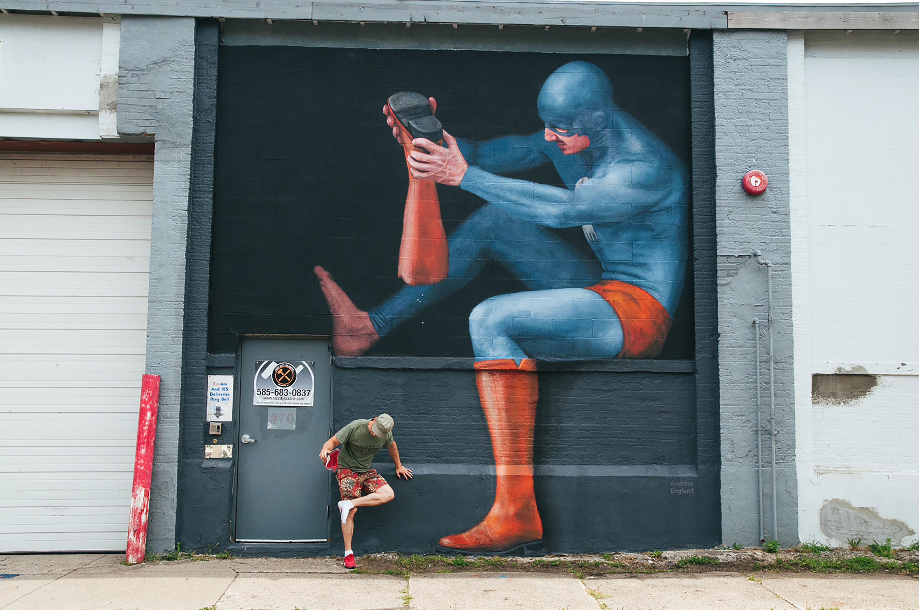Mural of a generic super hero getting pebbles out of a boot
