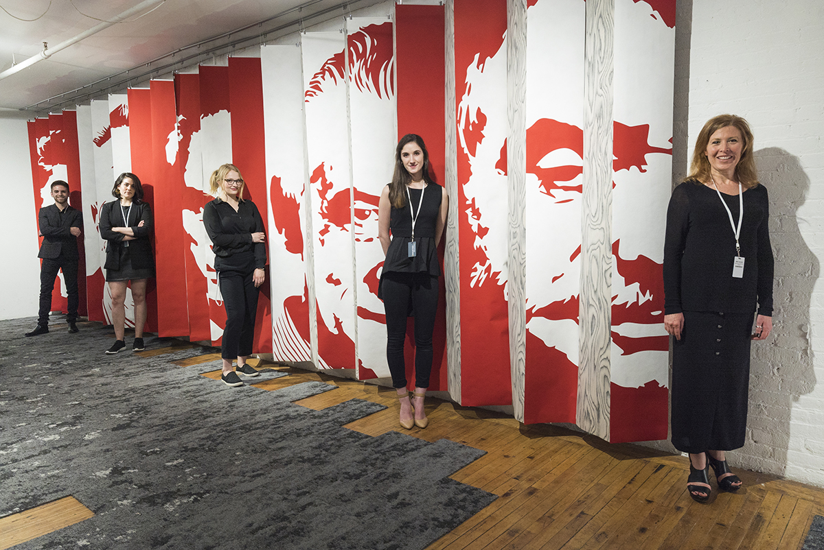 The five RIT interior designers behind Archivio in front of a panel wall they created for the exhibit