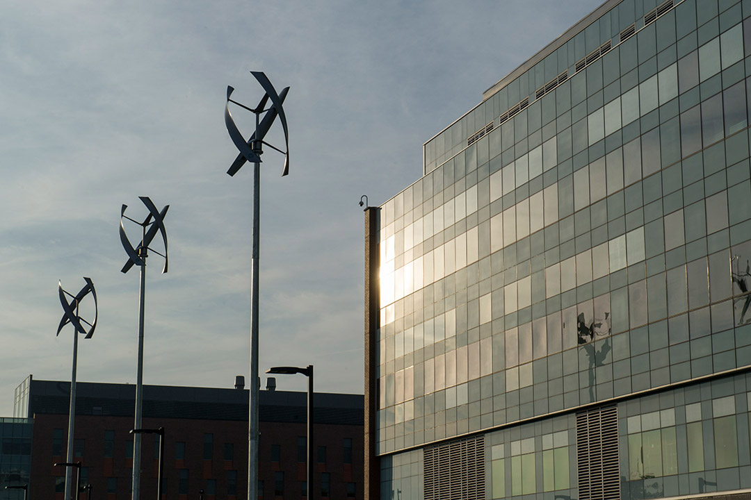 three wind turbines outside of glass building.