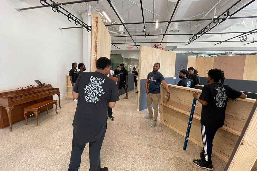 volunteers building wall frame for an art exhibit.