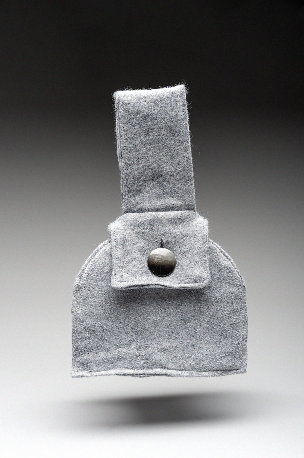 A grey bag design with a large button affixed to it.