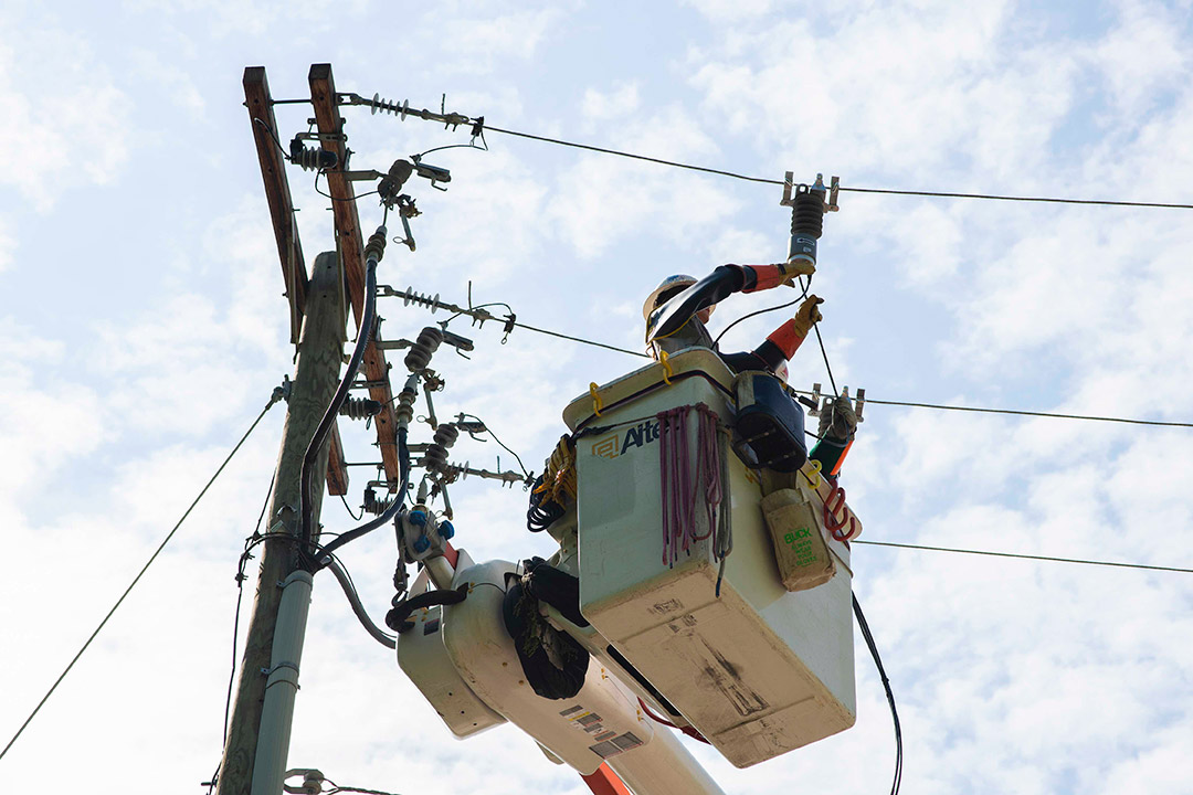 worker in cherry picker bucket working on power lines.