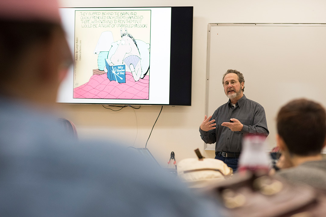 cartoonist giving lecture in front of a classroom.