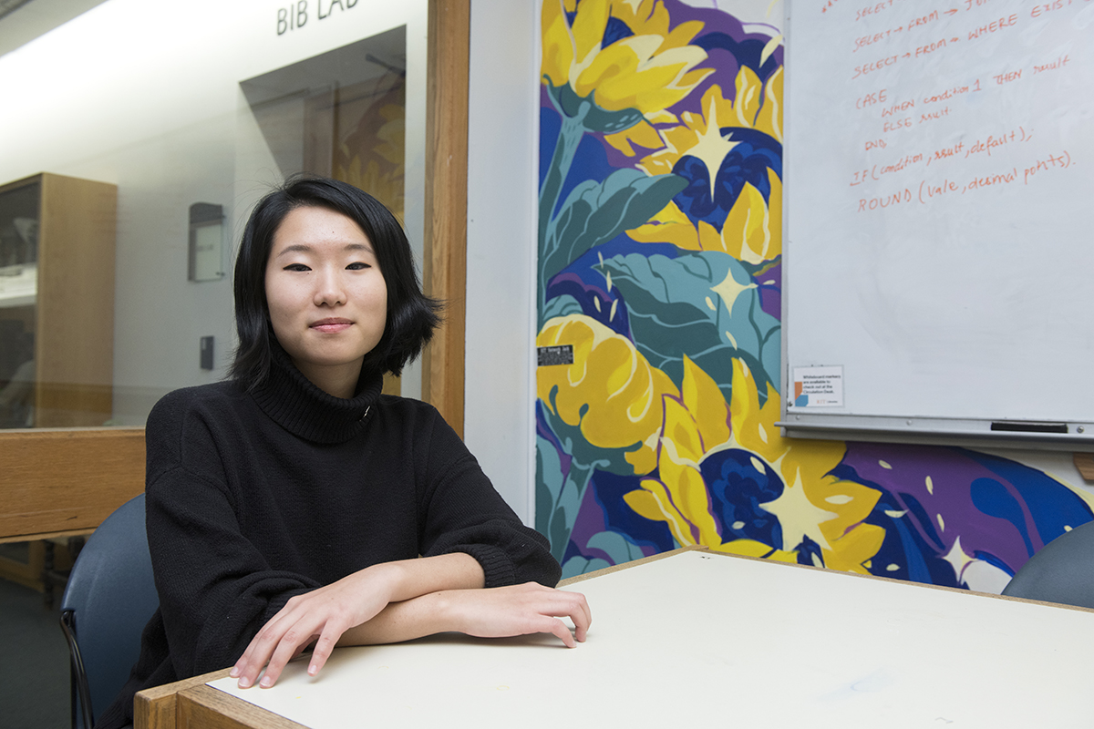 Juho Choi poses in front of the library mural she painted.