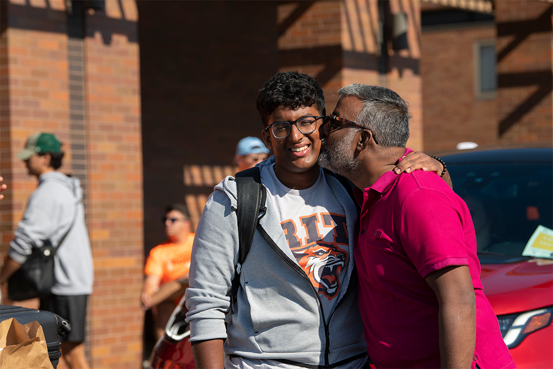 A father kisses an RIT student on the cheek.