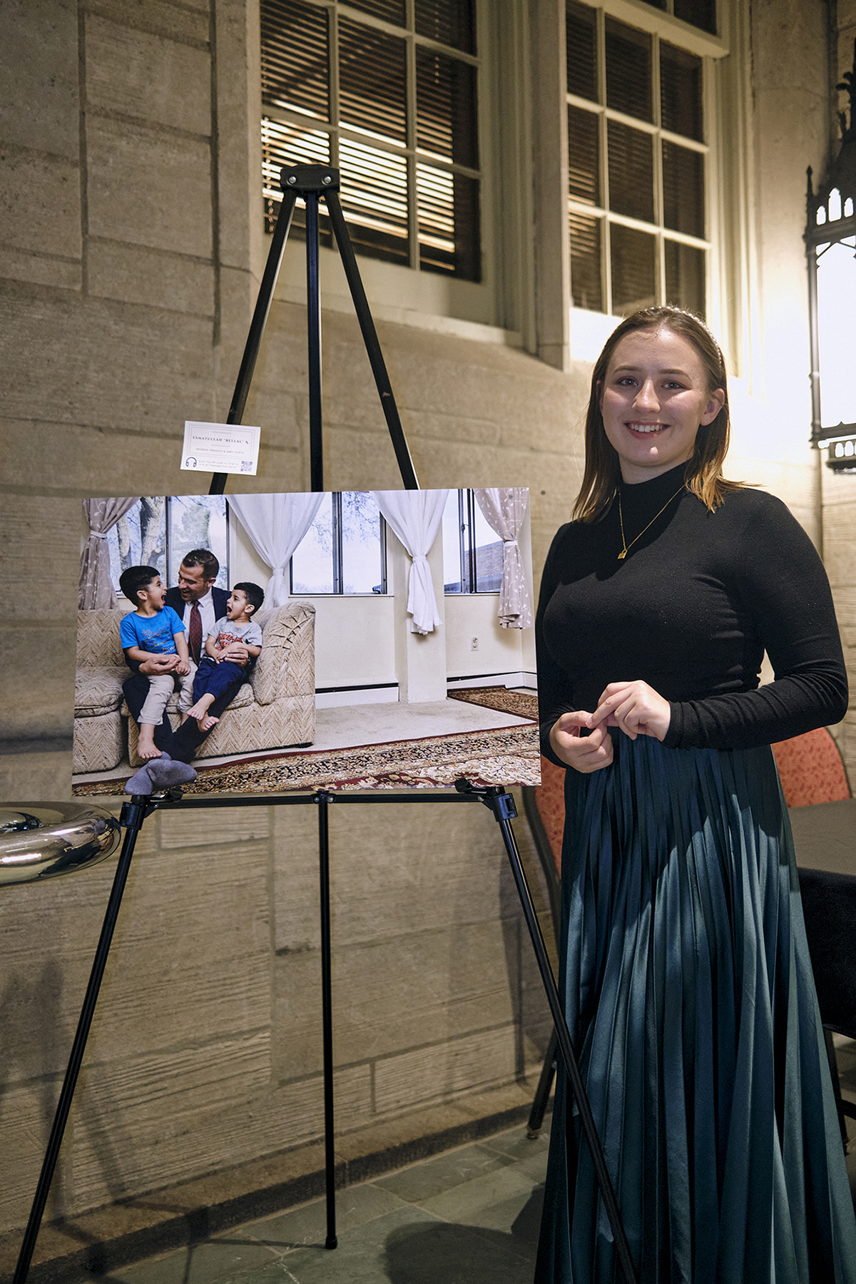 Abby Curtis stands next to one of her Afghan refugee portraits.