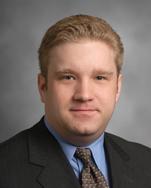 William Prentice stands in front of a grey background and looks at the camera