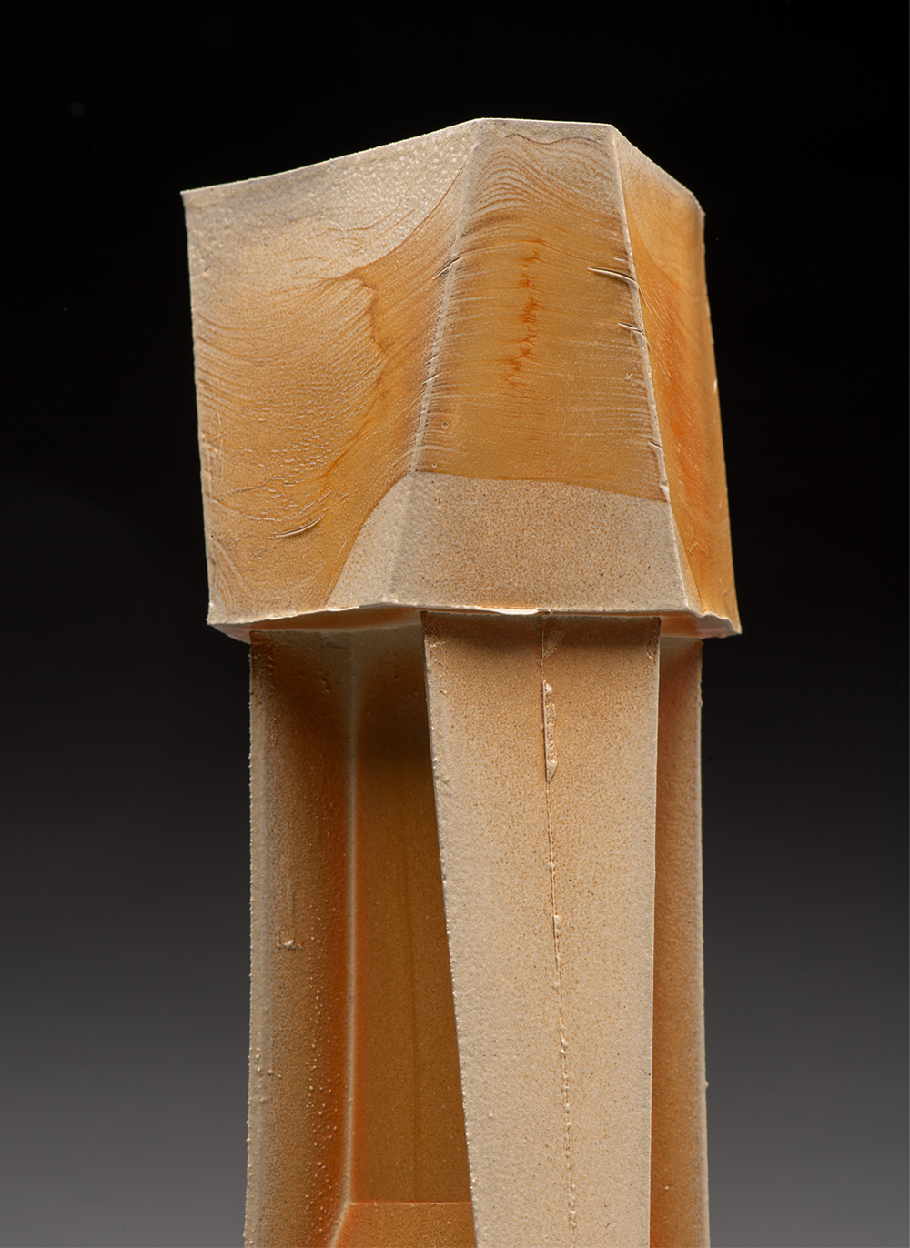 A detailed look at the top of a tall wooden sculpture inspired by industrial architecture.