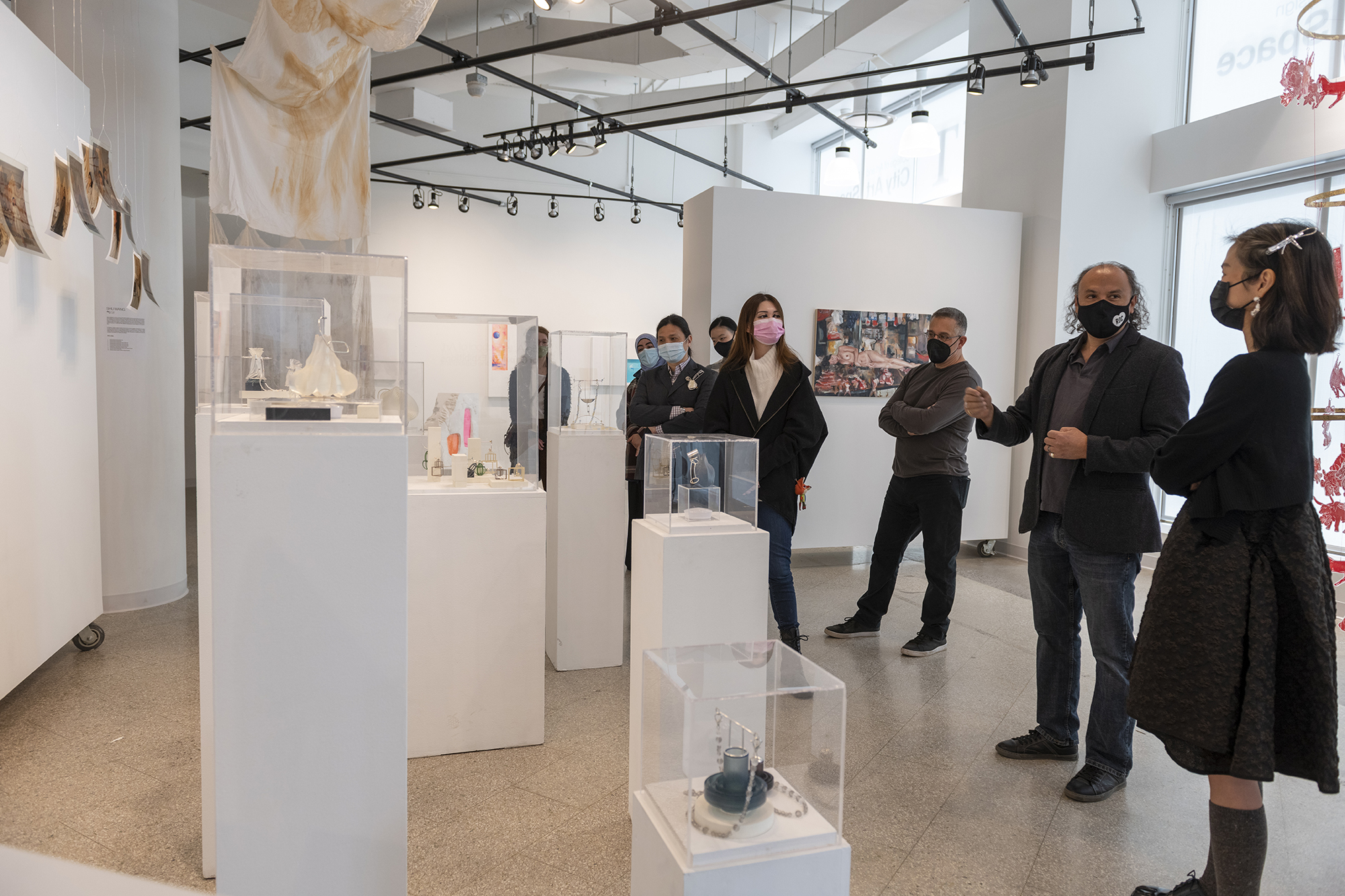 A group of people stand around an exhibit of metals and jewelry design.