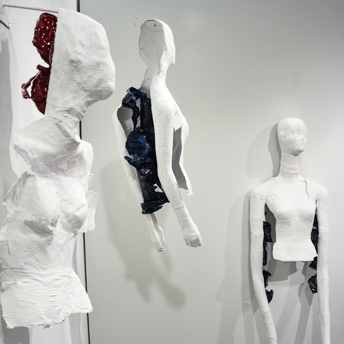 Three plaster mannequins rest on gallery walls