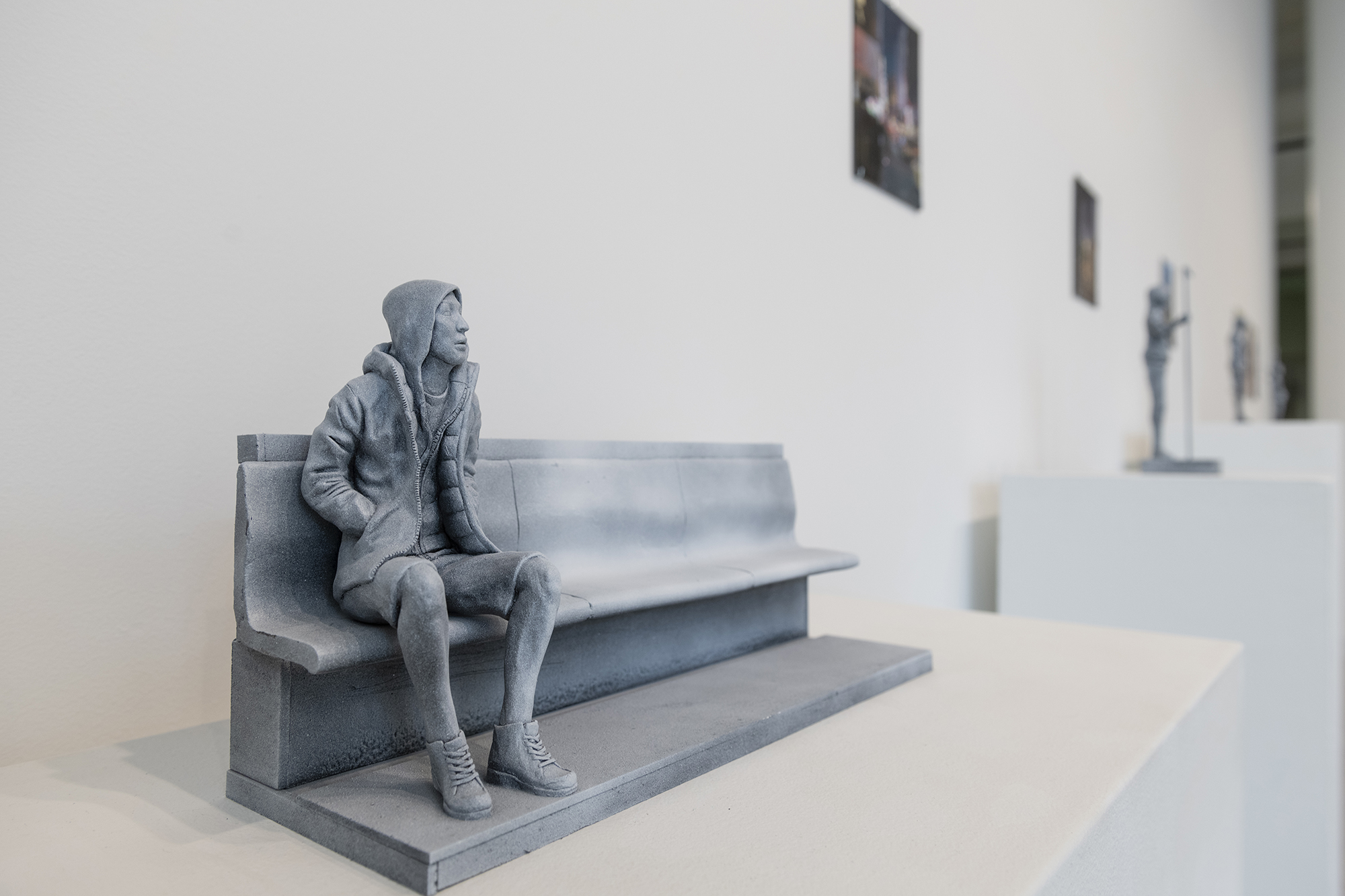 A sculpture of a person sitting on a bench.