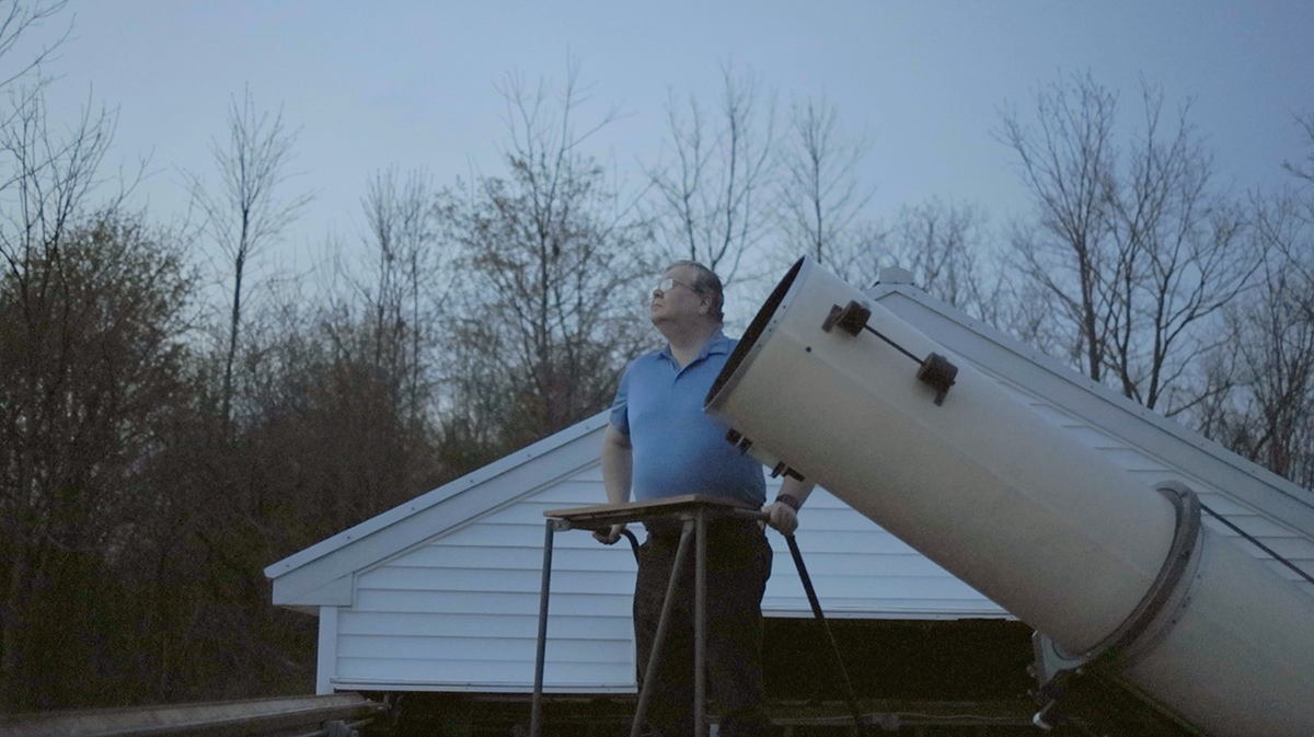 A man operates a large telescope.