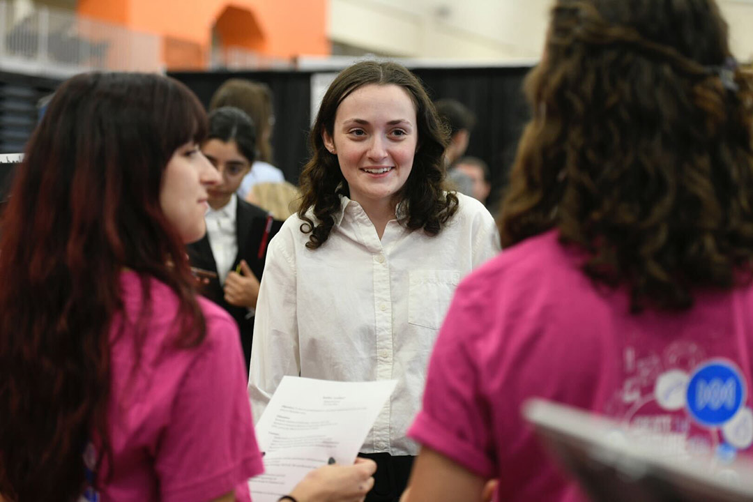 student talking to two recruiters at a job fair.