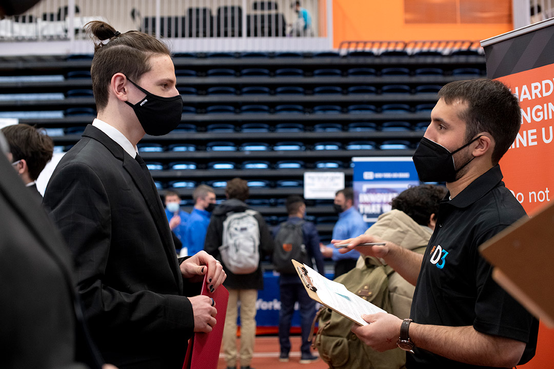 student and employer talking at a career fair.