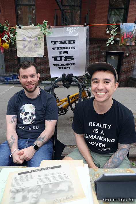 Louis Chavez and a friend pose for a photo while sitting outside.