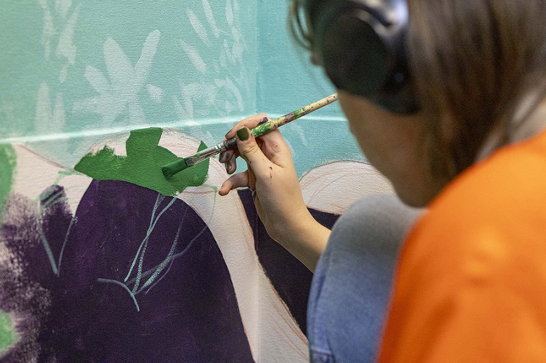 A detailed look at a student painting a mural.