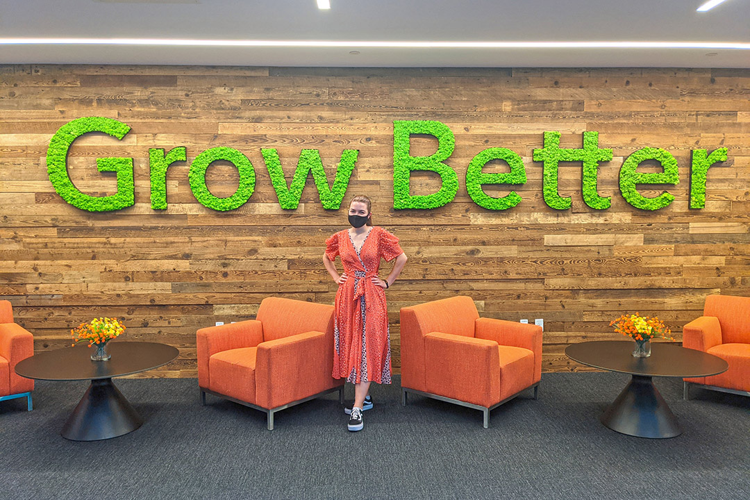 student standing in front of a wall with large letters that read Grow Better.