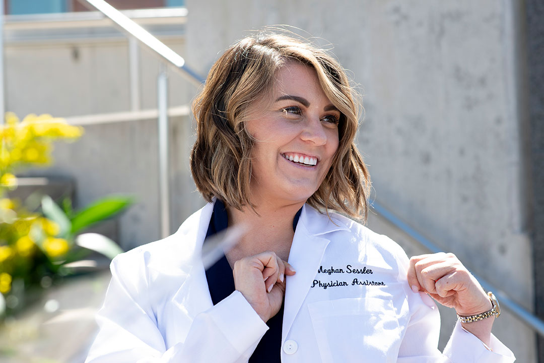 student poses for photo in her new white lab coat.