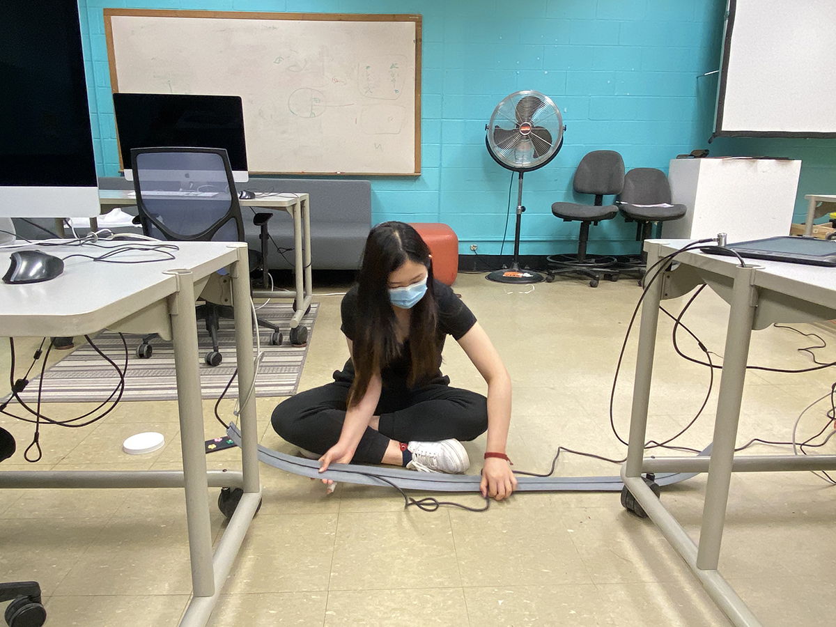 A student lays down tracks to hide wires in a computer lab.