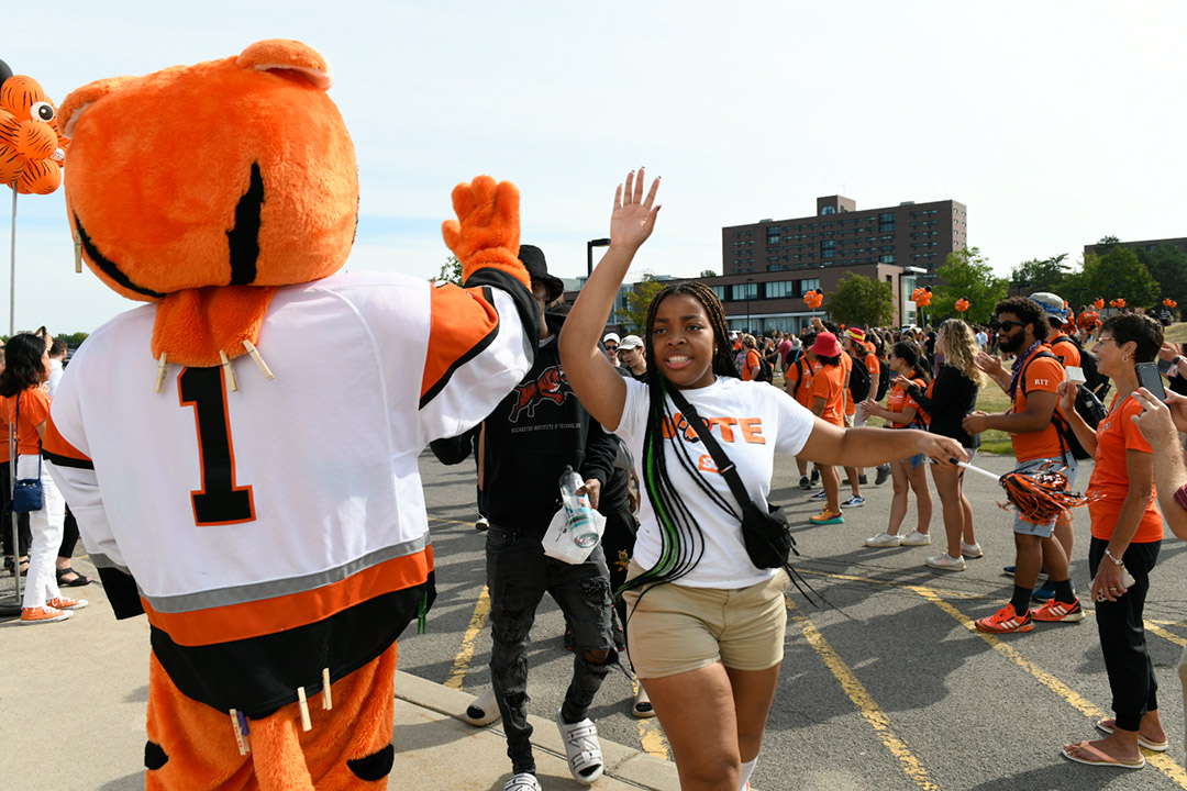 student high-fiving a tiger mascot.