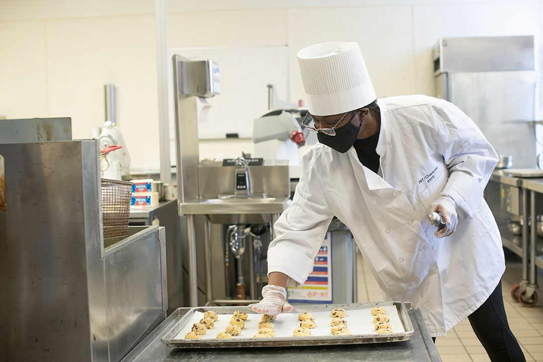 student flattening cookies on a baking sheet.