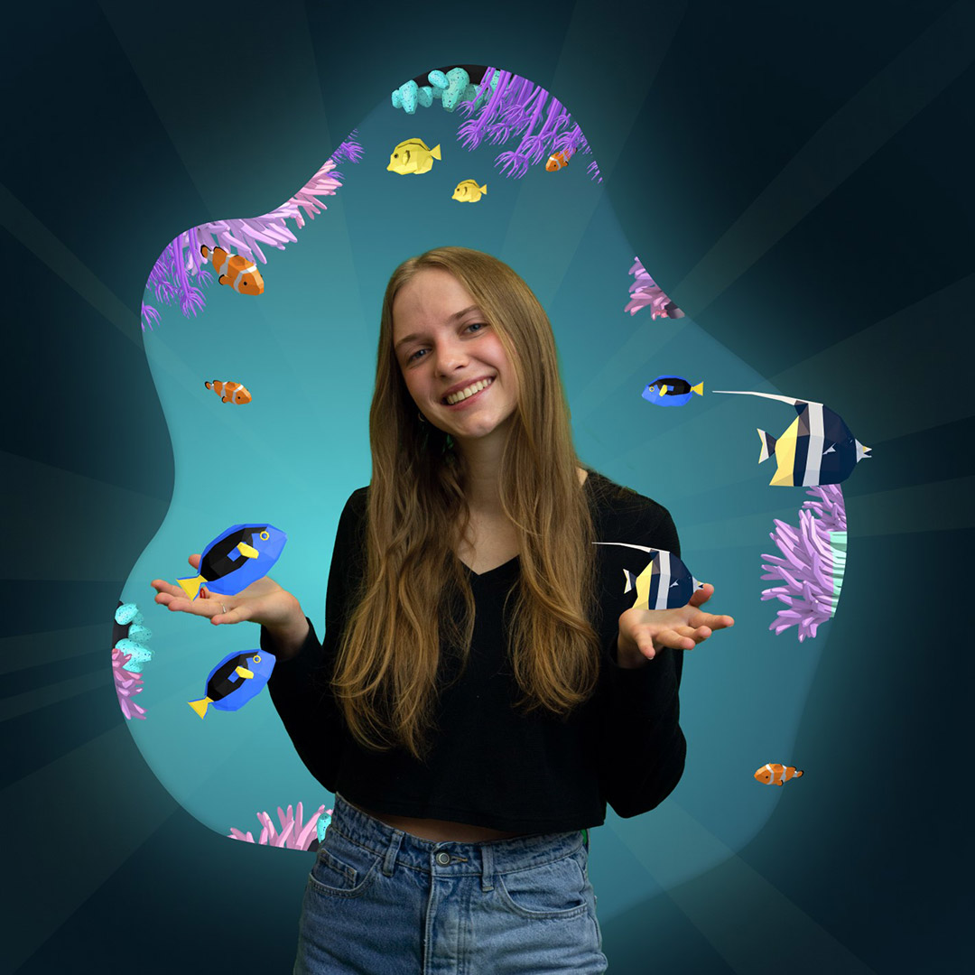 Student, umgeben von einer virtuellen Darstellung des Meereslebens.