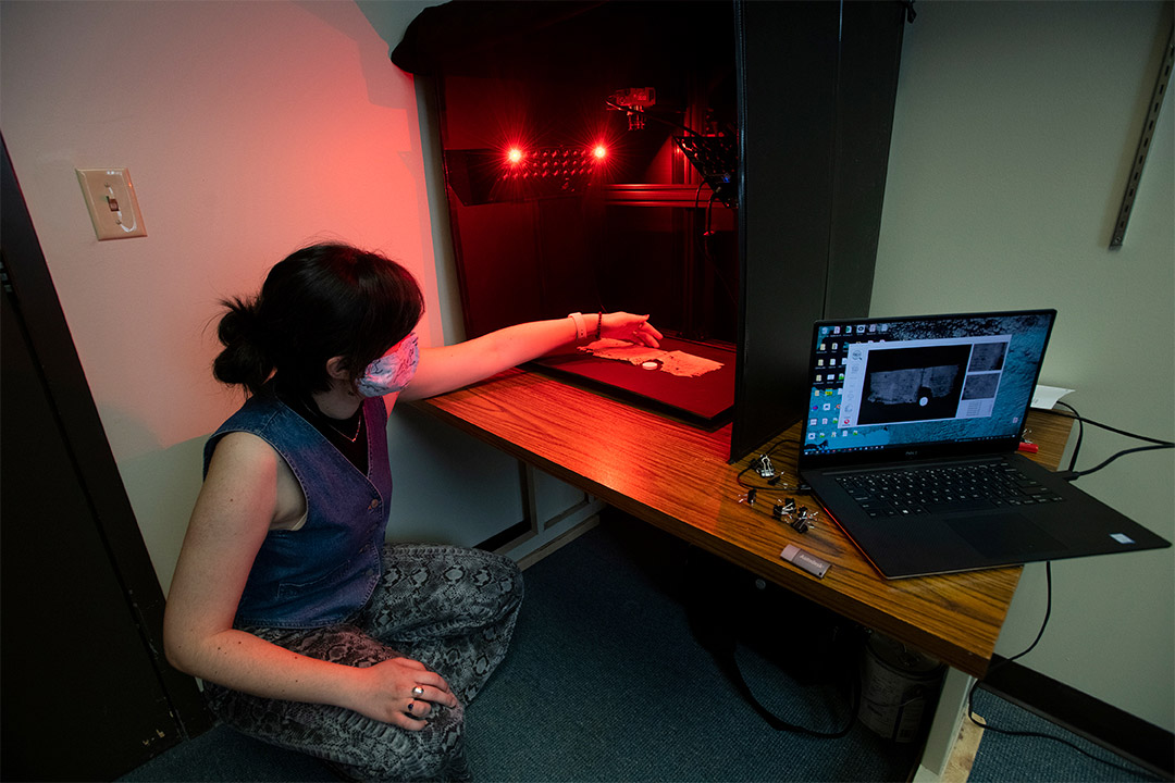 student looking at document under red lights.