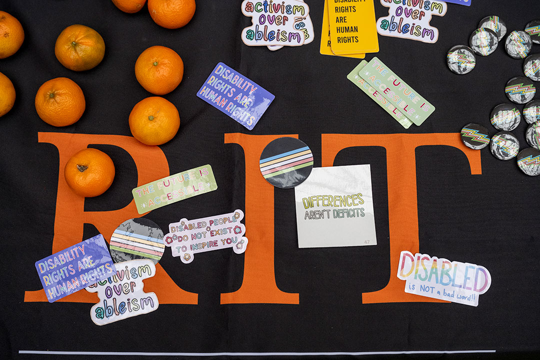 clementines, stickers, and buttons on a table with an RIT tablecloth.
