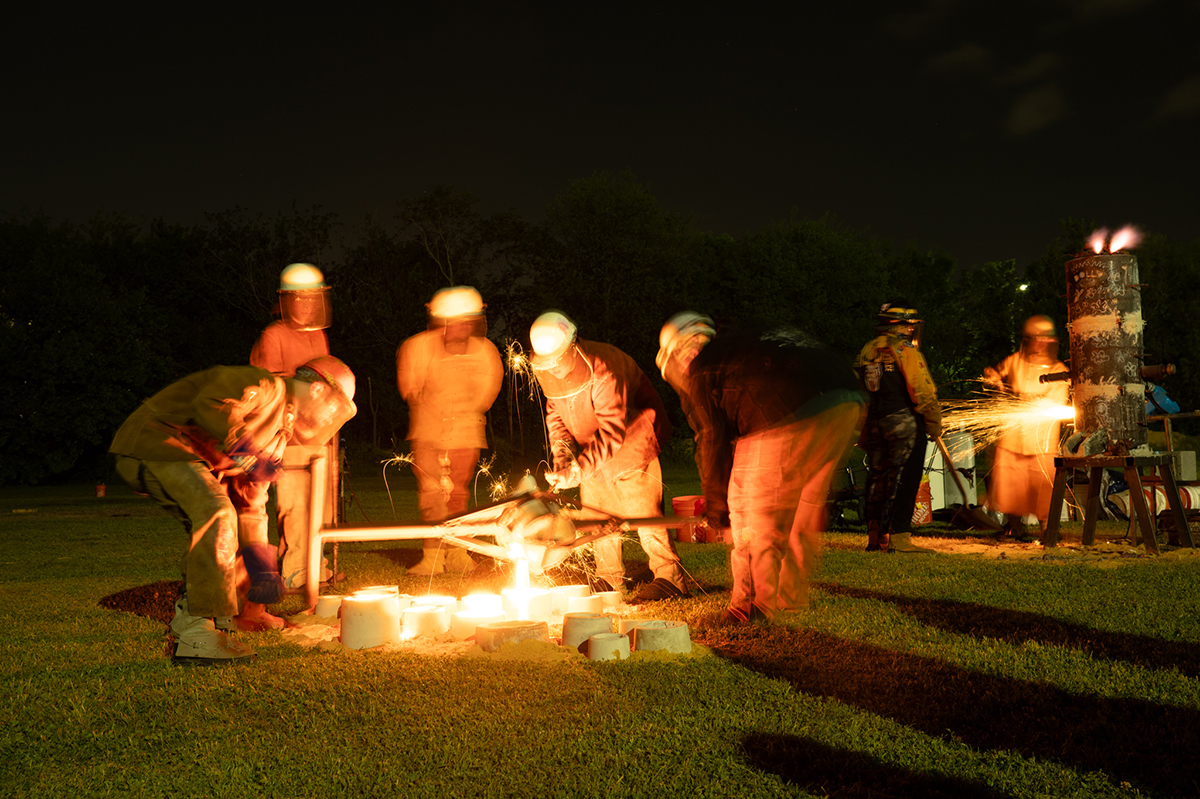 Students pour molten iron into molds.