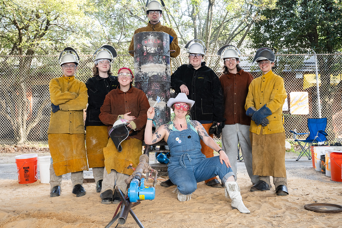 A group of students and faculty pose with a cupola furnace they made.