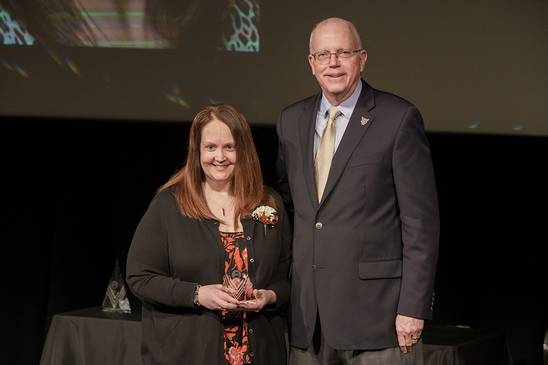 award winner and President Munson posing on stage.